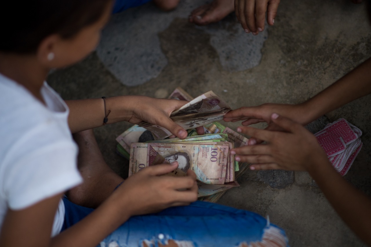 En Venezuela quitan seis ceros al bolívar; niños utilizan los billetes para jugar cartas