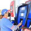 una mujer opera una máquina dispensadora de gasolina