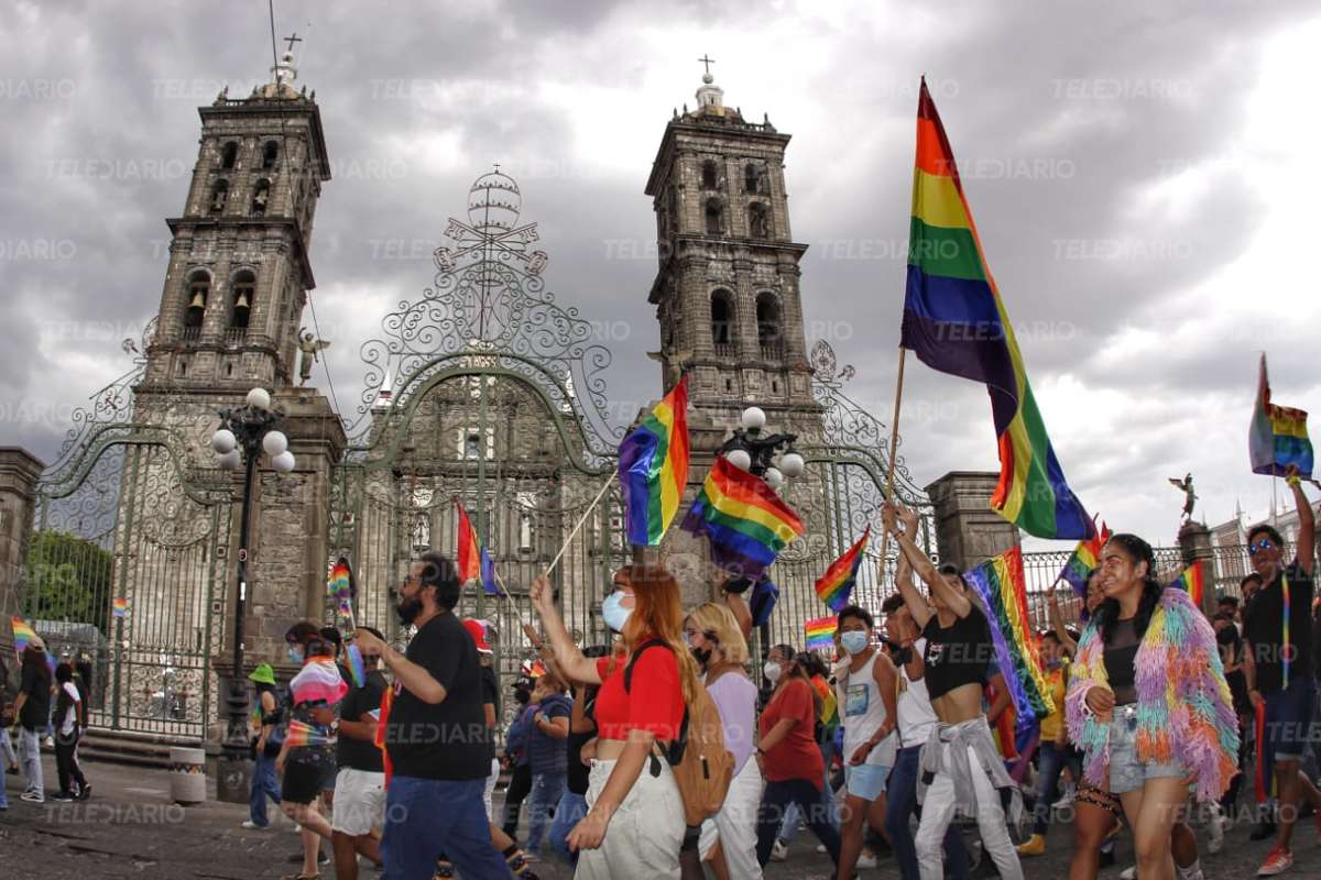 Personas con banderas de la comunidad LGBTTTIQ marchan frente a la Catedral de Puebla / Melanie Torres