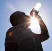 Persona tomando agua bajo el sol.