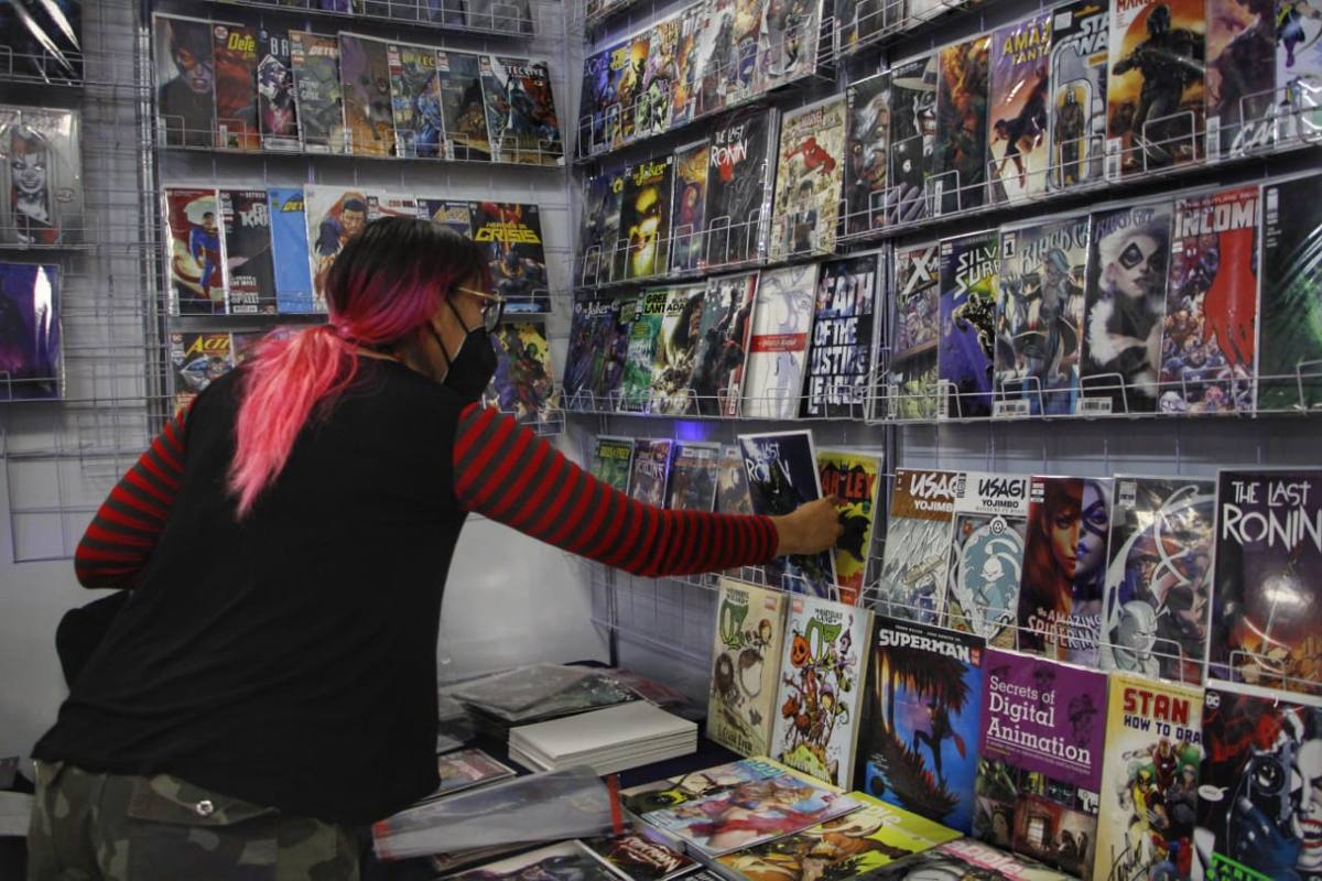 Un joven toma un cómic de un stand en la Ficómic BUAP 2022 / Melanie Torres