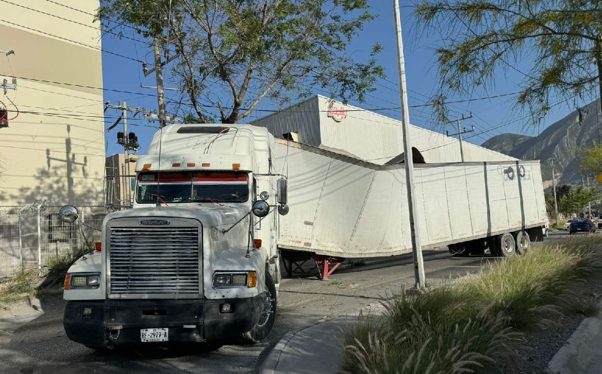 Tráiler queda atorado al pasar por árbol en colonia El Frutal en Santa Catarina. | Marcela Cuevas