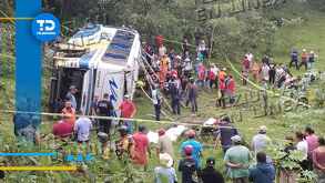 personas ayudan a pasajeros de un autobús volcado