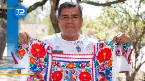 un artesano muestra una prenda con bordados