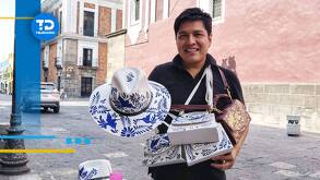 un artesano muestra bolsas y sombreros pintados