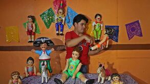 un artesano muestra muñecos hechos de cartonería