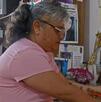 una mujer coloca una veladora en un altar con fotografías