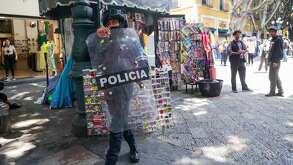 un policia pasa por un puesto ambulante en el centro de puebla