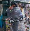 un policia pasa por un puesto ambulante en el centro de puebla