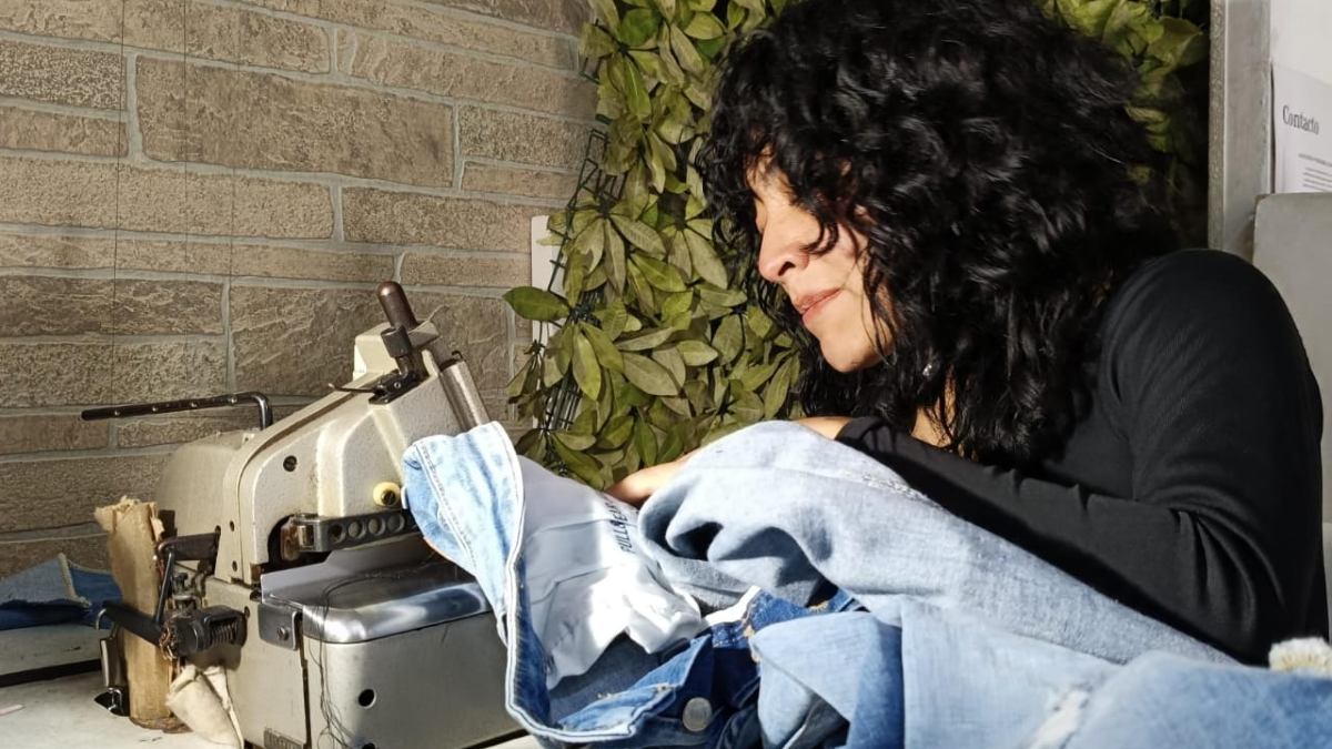 una mujer cosiendo una prenda en máquina una mujer cosiendo una prenda en máquina