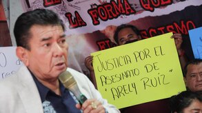 un hombre hablando con un micrófono y un hombre sosteniendo una cartulina