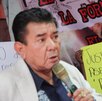 un hombre hablando con un micrófono y un hombre sosteniendo una cartulina