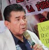un hombre hablando con un micrófono y un hombre sosteniendo una cartulina