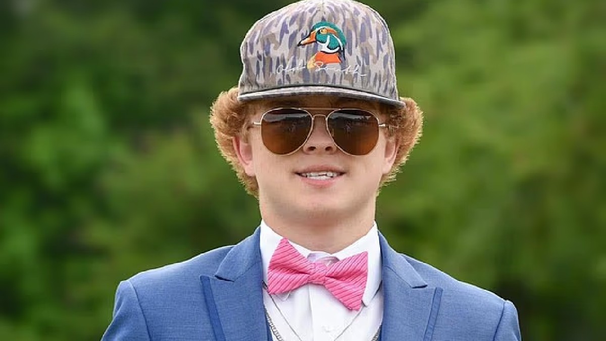 un joven con traje azul, gorra y lentes un joven con traje azul, gorra y lentes