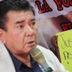 un hombre hablando con un micrófono y un hombre sosteniendo una cartulina