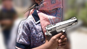 un niño con el rostro cubierto sosteniendo una arma