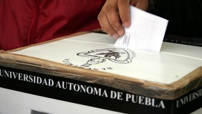 una persona colocando una boleta en una urna