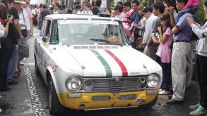 un auto clásico en una calle con personas