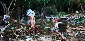 un hombre sentado entre varios escombros por una inundación