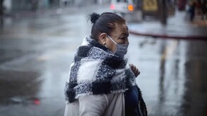 Mujer caminando con cubrebocas con lluvias y bajas temperaturas en la Ciudad de México.