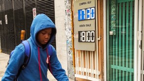 Un niño pasa enfrente de la casa de cambio del dólar en la Ciudad de México.