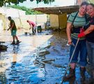 Dos mujeres realizan labores de limpieza en sus casas, luego de que fueran cubiertas por el lodo, agua y basura de la corriente del río Cazones en Poza Rica.