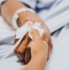 Mano de una mujer enferma recostada en una camilla de hospital. Mano de una mujer enferma recostada en una camilla de hospital.