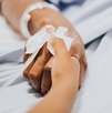 Mano de una mujer enferma recostada en una camilla de hospital. Mano de una mujer enferma recostada en una camilla de hospital.