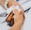 Mano de una mujer enferma recostada en una camilla de hospital. Mano de una mujer enferma recostada en una camilla de hospital.