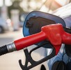 una manguera de gasolina despachando gasolina en una gasolinera a un auto azul una manguera de gasolina despachando gasolina en una gasolinera a un auto azul