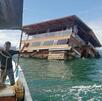un restaurante de madera flotando en el mar abierto y unos pescadores un restaurante de madera flotando en el mar abierto y unos pescadores