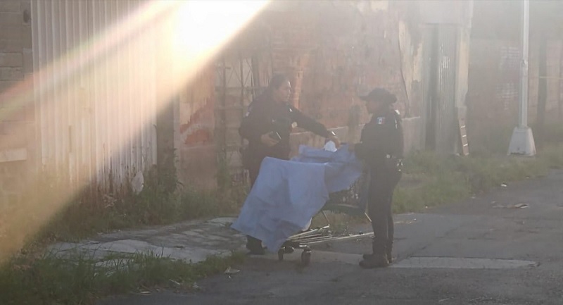 Policías con el cadáver de una mujer cubierto con una sábana en Puebla capital.