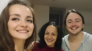 En la imagen aparece Lolita Cortés con una blusa roja y lentes, junto a sus dos hijos, uno de ellos con una playera gris y el otro con blusa a rayas.