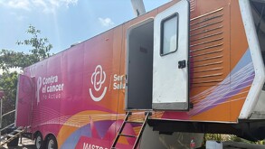 Vista lateral de una Unidad Móvil de Salud de color naranja y magenta con el mensaje 