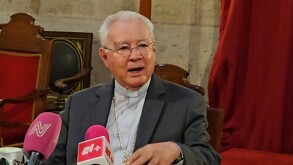 El Cardenal Robles Ortega, un hombre mayor con traje oscuro y alzacuellos, está sentado dando una declaración ante dos micrófonos con logotipos de TELEDIARIO