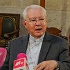 El Cardenal Robles Ortega, un hombre mayor con traje oscuro y alzacuellos, está sentado dando una declaración ante dos micrófonos con logotipos de TELEDIARIO El Cardenal Robles Ortega, un hombre mayor con traje oscuro y alzacuellos, está sentado dando una declaración ante dos micrófonos con logotipos de TELEDIARIO
