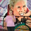 Una mujer en playera rosa posa frente a un mural de boxeo vibrante que muestra a una campeona sonriente con un cinturón. Se aprecian las cuerdas y esquinas Una mujer en playera rosa posa frente a un mural de boxeo vibrante que muestra a una campeona sonriente con un cinturón. Se aprecian las cuerdas y esquinas