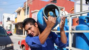 Hombre carga tanque de gas, se transporta en un camión repartidor de gas LP, para consumo habitacional.