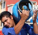 Hombre carga tanque de gas, se transporta en un camión repartidor de gas LP, para consumo habitacional.