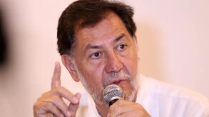En la imagen aparece Fernandez Noroña con una camisa blanca y un micrófono.