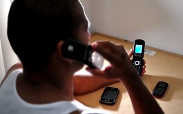 Hombre con celulares realizando llamadas de extorsión