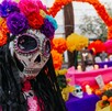 Primer plano de una figura de La Catrina con un cráneo decorado y una corona de flores de papel brillantes (rosa, morado, azul). Un altar del Día de Muertos Primer plano de una figura de La Catrina con un cráneo decorado y una corona de flores de papel brillantes (rosa, morado, azul). Un altar del Día de Muertos