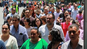 Personas en la calle saliendo de un edificio por un sismo.