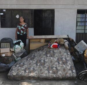 una mujer afuera de una casa inundada por las lluvias en la sierra norte de puebla