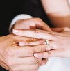 En la imagen se pueden ver las manos de un hombre poniendo el anillo de bodas a su prome En la imagen se pueden ver las manos de un hombre poniendo el anillo de bodas a su prome