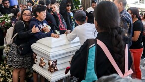 Personas llorando junto al féretro de 