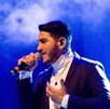 En la imagen aparece Joan Sebastián Alarcón, quien se encuentra con un atuendo en color negro sosteniendo un micrófono, en lo que parece ser un concierto. En la imagen aparece Joan Sebastián Alarcón, quien se encuentra con un atuendo en color negro sosteniendo un micrófono, en lo que parece ser un concierto.