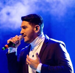 En la imagen aparece Joan Sebastián Alarcón, quien se encuentra con un atuendo en color negro sosteniendo un micrófono, en lo que parece ser un concierto. En la imagen aparece Joan Sebastián Alarcón, quien se encuentra con un atuendo en color negro sosteniendo un micrófono, en lo que parece ser un concierto.