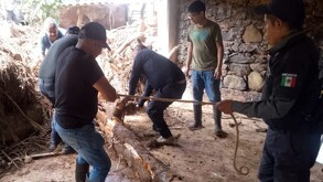 Hombres trabajan en labores de rescate entre escombros provocados por lluvias en Sierra Norte de Puebla.