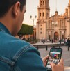 Hombre sentado en las afueras de la catedral de Guadalajara revisando app de citas Hombre sentado en las afueras de la catedral de Guadalajara revisando app de citas